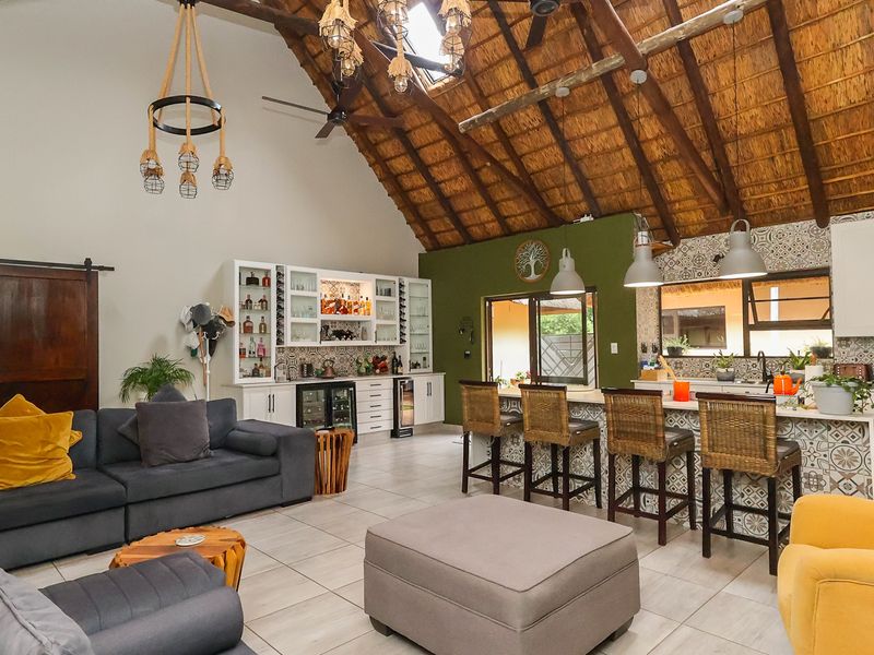 Spacious open-plan living area featuring a high vaulted thatched ceiling with exposed beams, a modern kitchen with island, and integrated cabinetry.