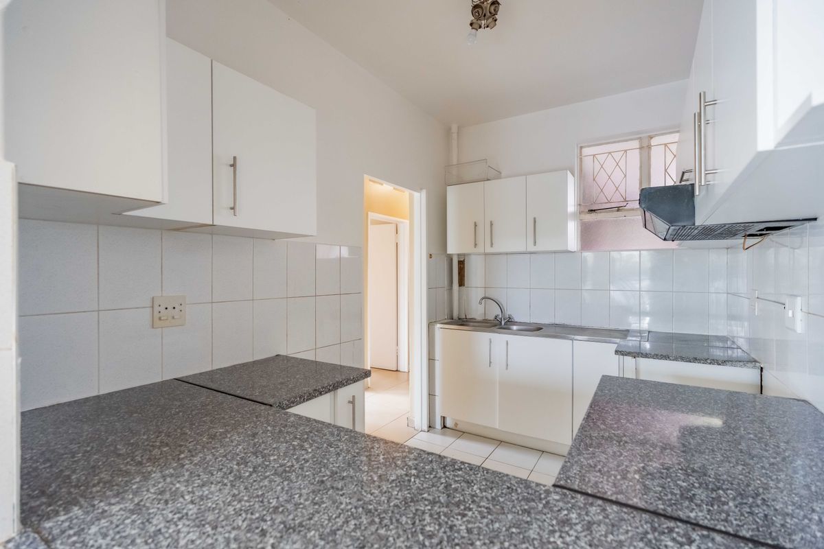 A functional kitchen featuring white cabinetry, granite countertops, a stainless steel sink, and a tiled backsplash, offering a clean and practical workspace.