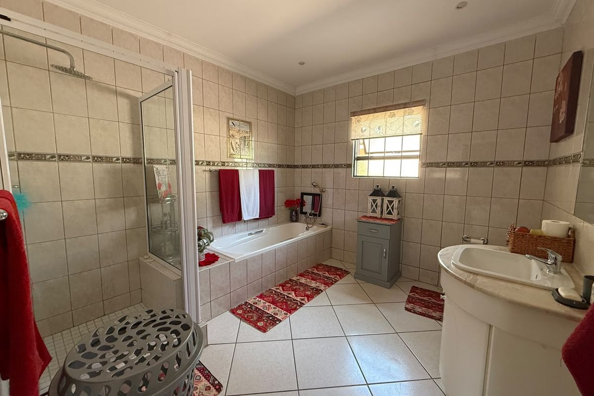 Spacious bathroom featuring a built-in bathtub, separate walk-in shower, and a vanity unit with neutral ceramic tiling throughout.