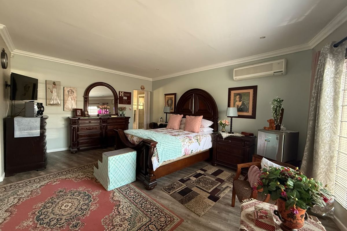 Spacious bedroom featuring laminate flooring, recessed downlighting, and a wall-mounted air conditioning unit.