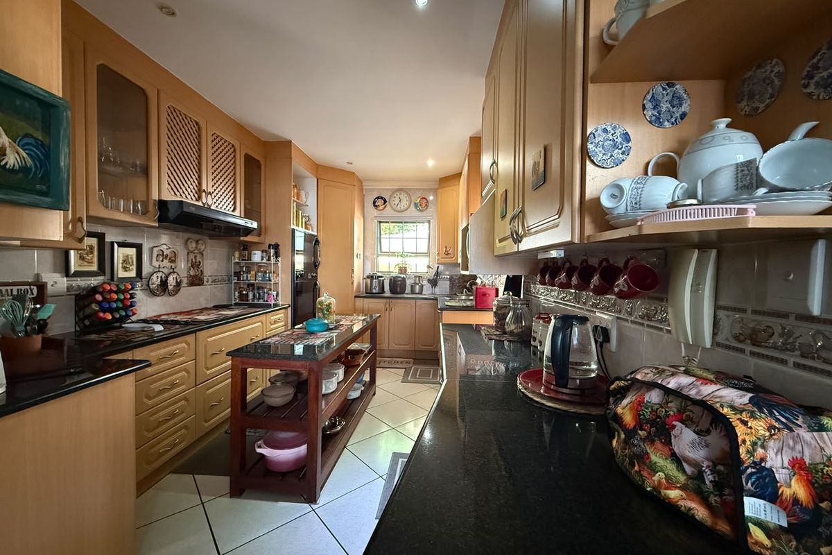 A functional kitchen featuring extensive wooden cabinetry, granite countertops, and tiled flooring, offering ample storage and workspace for meal preparation.