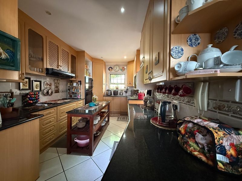 A functional kitchen featuring extensive wooden cabinetry, granite countertops, and tiled flooring, offering ample storage and workspace for meal preparation.