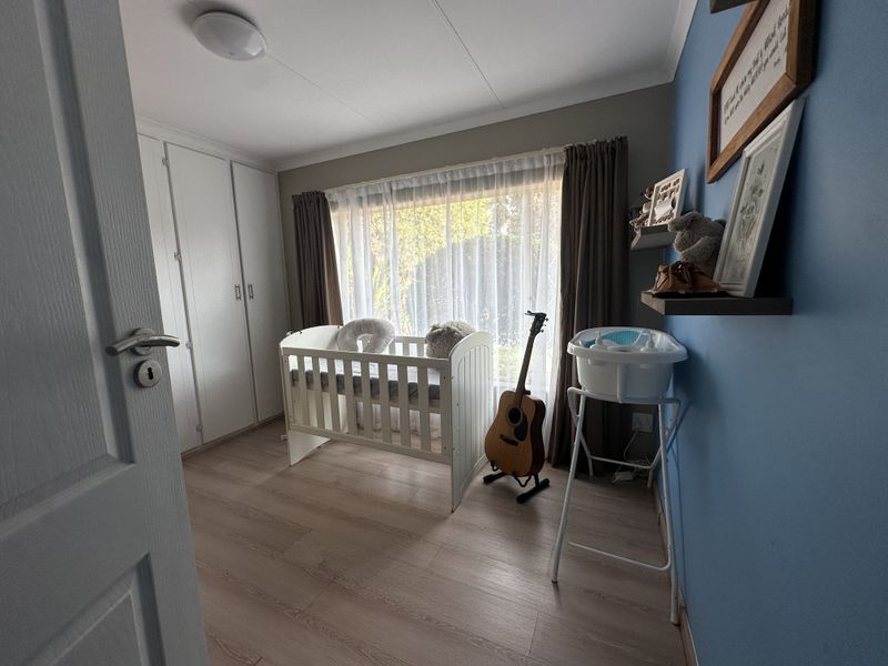 A well-maintained bedroom featuring laminate flooring, built-in cupboards, and a large window providing natural light.