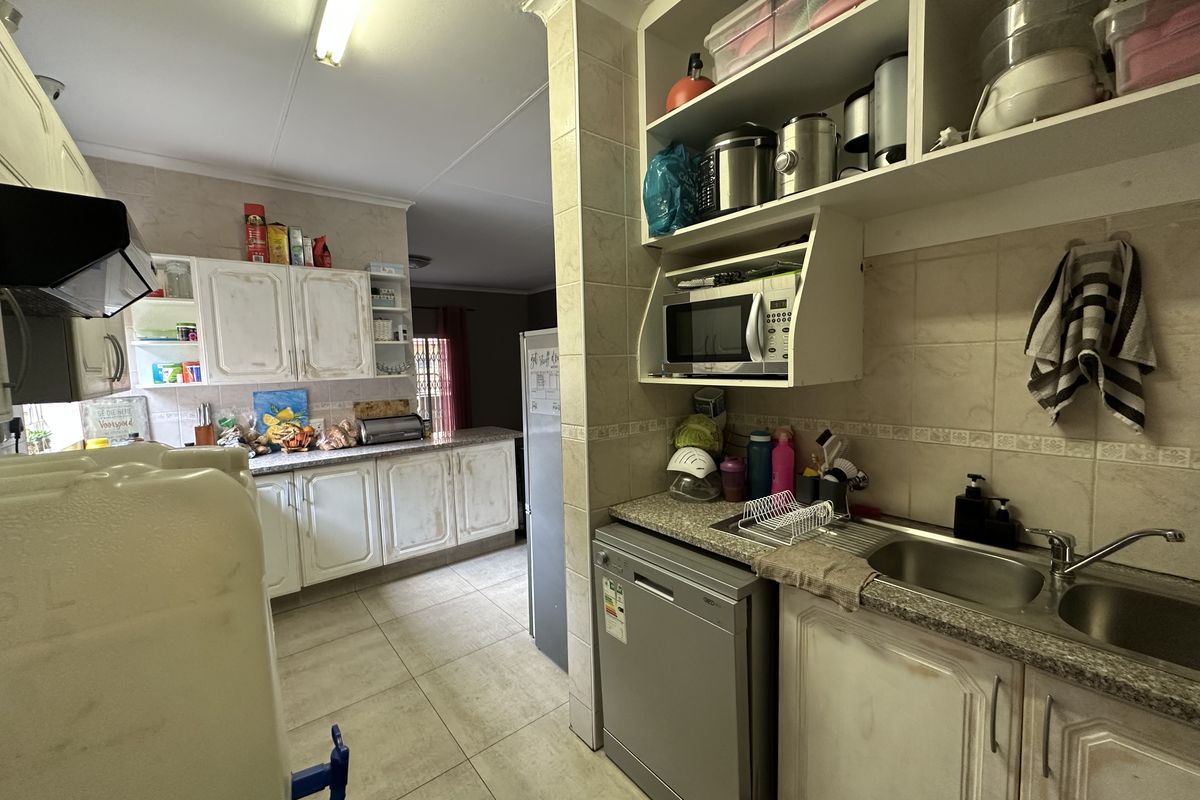 A functional kitchen featuring granite countertops, double sink, built-in cabinetry, and tiled finishes, offering potential for modernization and aesthetic updates.