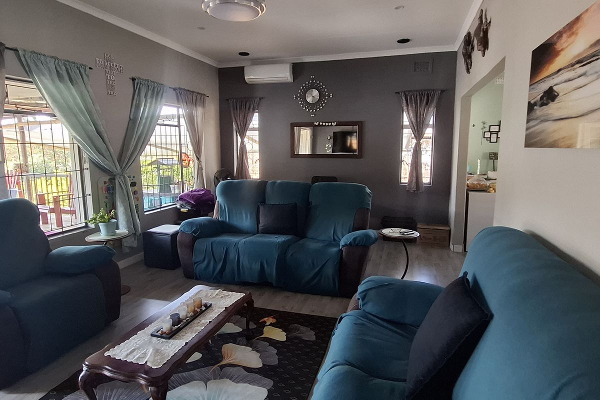 A comfortable living room featuring laminate flooring, recessed lighting, and a wall-mounted split-system air conditioner, providing a functional and well-lit space.