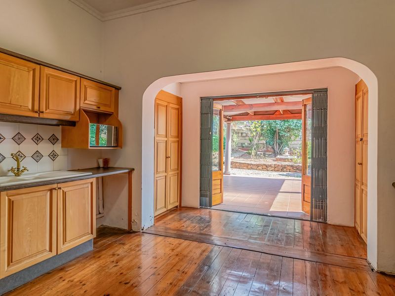 A spacious kitchen featuring wooden cabinetry, hardwood flooring, and direct access to an outdoor patio area through a wide arched doorway.
