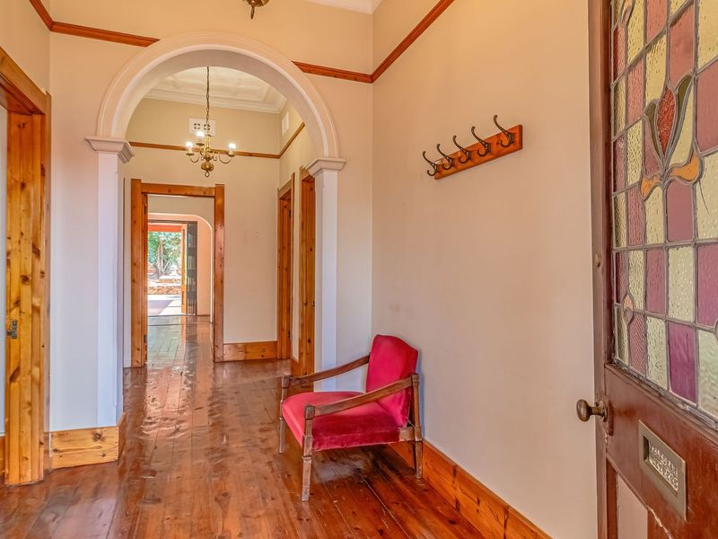 Welcoming entrance hall featuring original timber flooring, decorative archway, and a classic stained glass front door, leading through to the home's living areas.