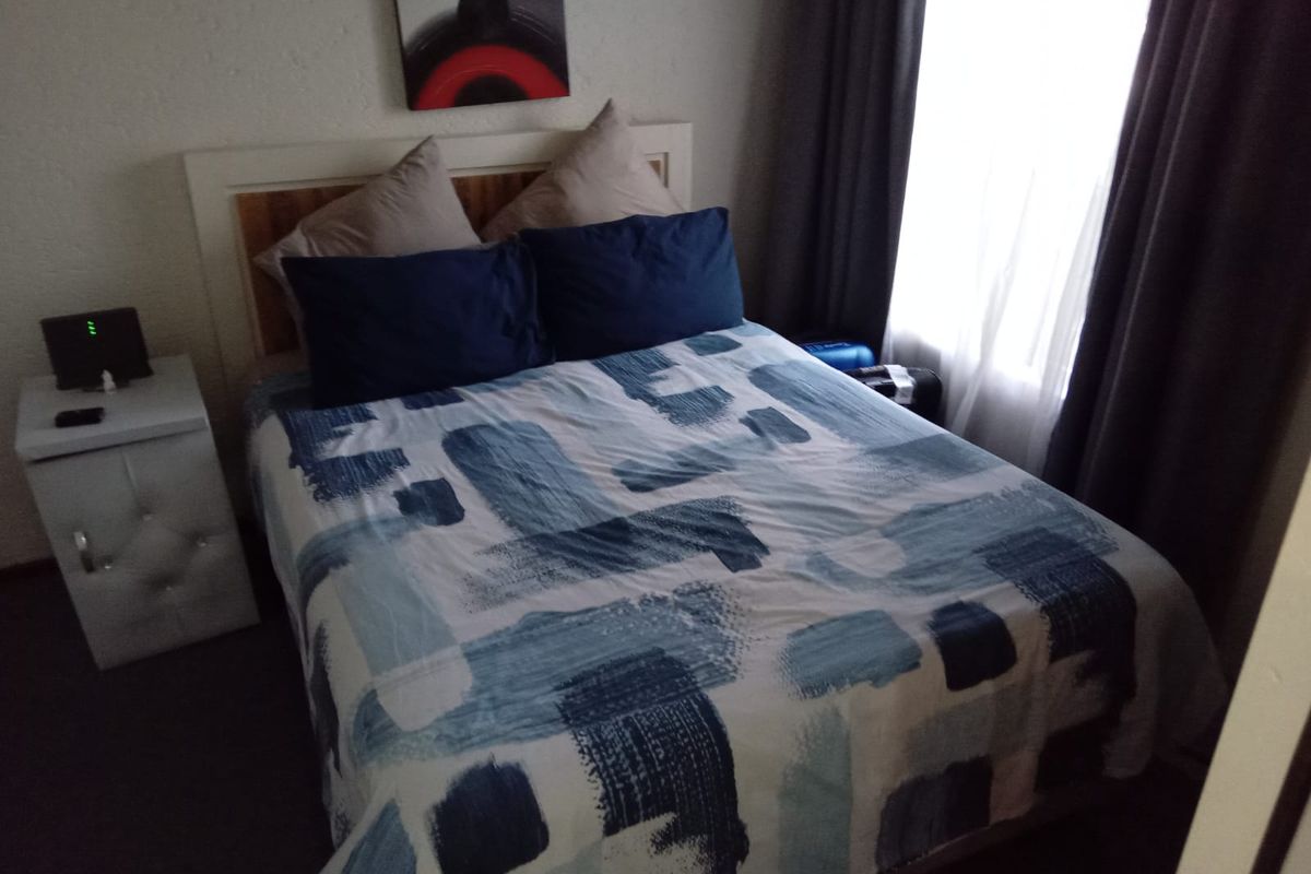 A compact bedroom featuring a window with curtains and neutral wall finishes.