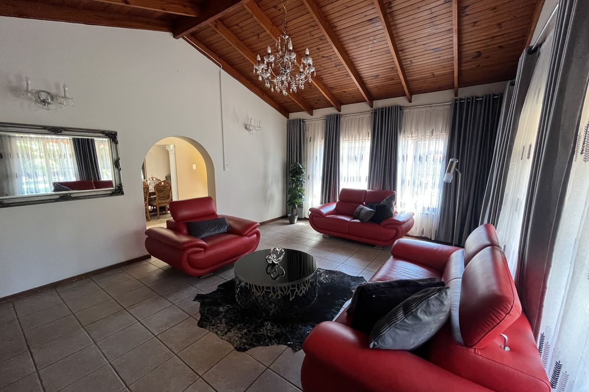 Spacious living room featuring a high exposed timber raked ceiling, ceramic tiled flooring, and an elegant arched entryway leading to the dining area.