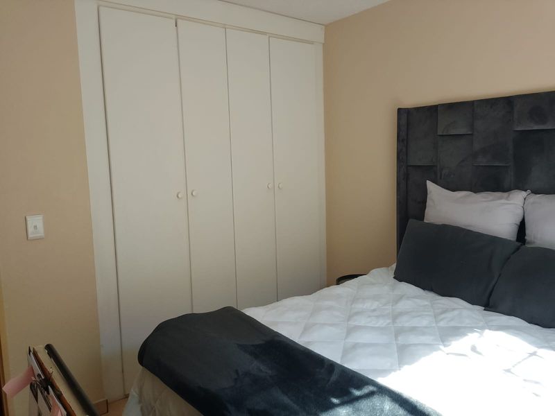 A bedroom featuring a built-in wardrobe with white doors and neutral wall tones.