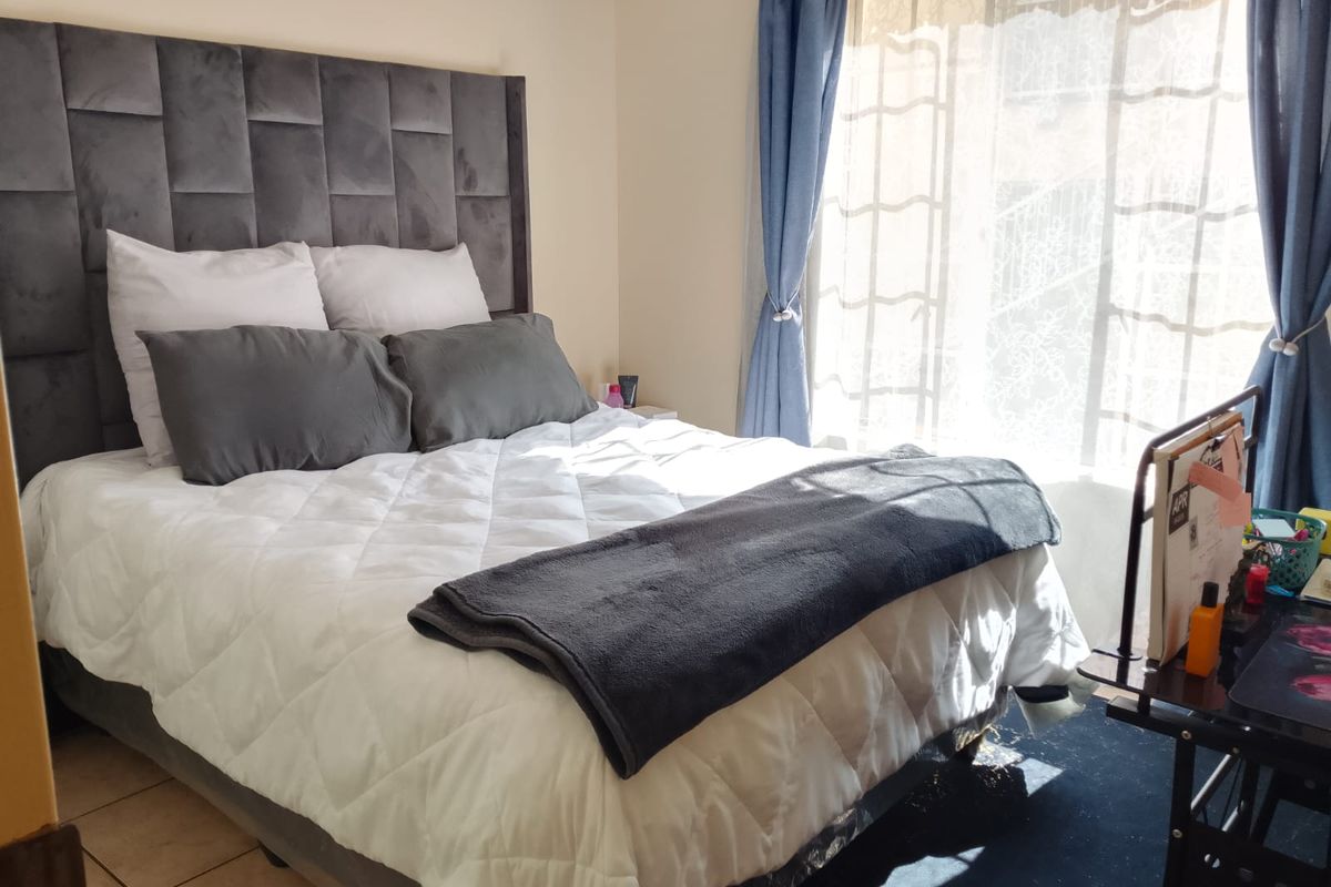 A well-lit bedroom featuring tiled flooring and a large window with natural light, providing a comfortable and functional living space.
