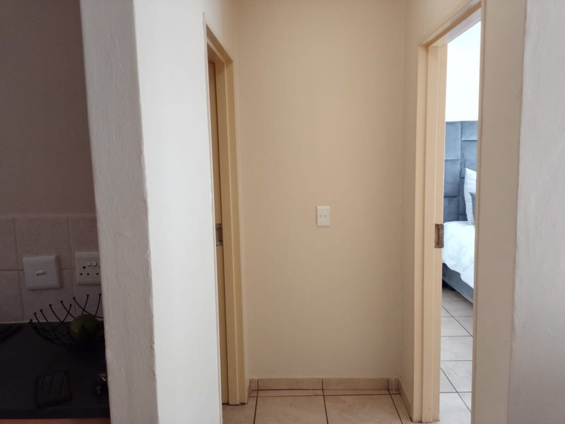 A functional hallway area connecting rooms, featuring neutral wall finishes and tiled flooring.