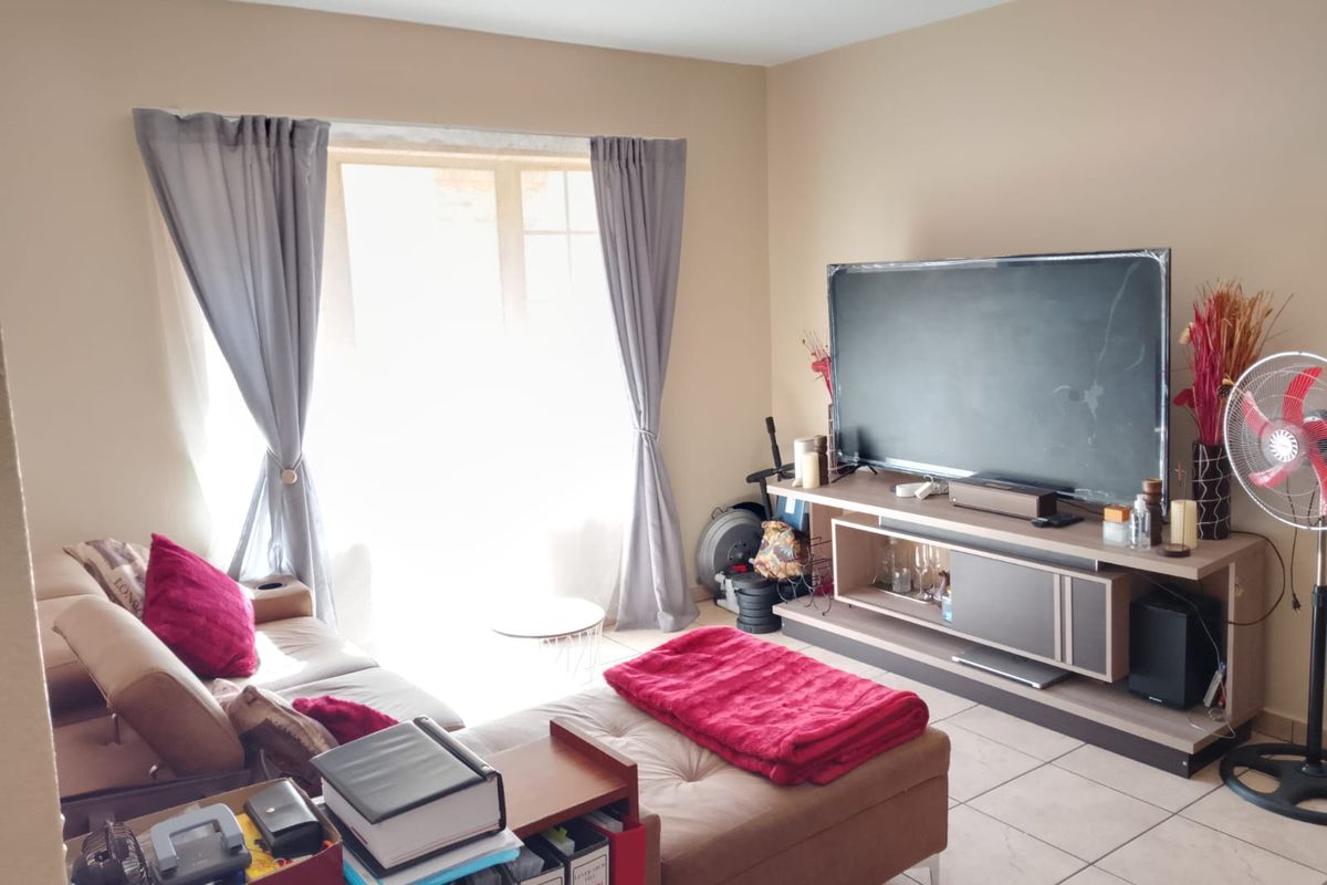 A living room featuring tiled flooring and a sliding glass door that provides natural light.