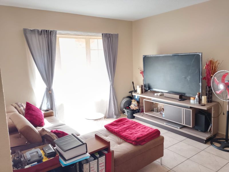 A living room featuring tiled flooring and a sliding glass door that provides natural light.