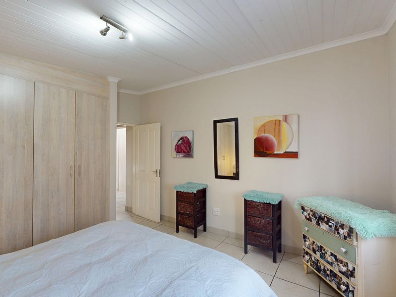 A bedroom featuring built-in cupboards, tiled flooring, and a tongue and groove ceiling with track lighting.