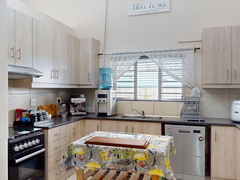 Functional kitchen featuring light wood-look cabinetry, dark countertops, tiled backsplash, and integrated space for appliances, offering a practical layout for daily use.