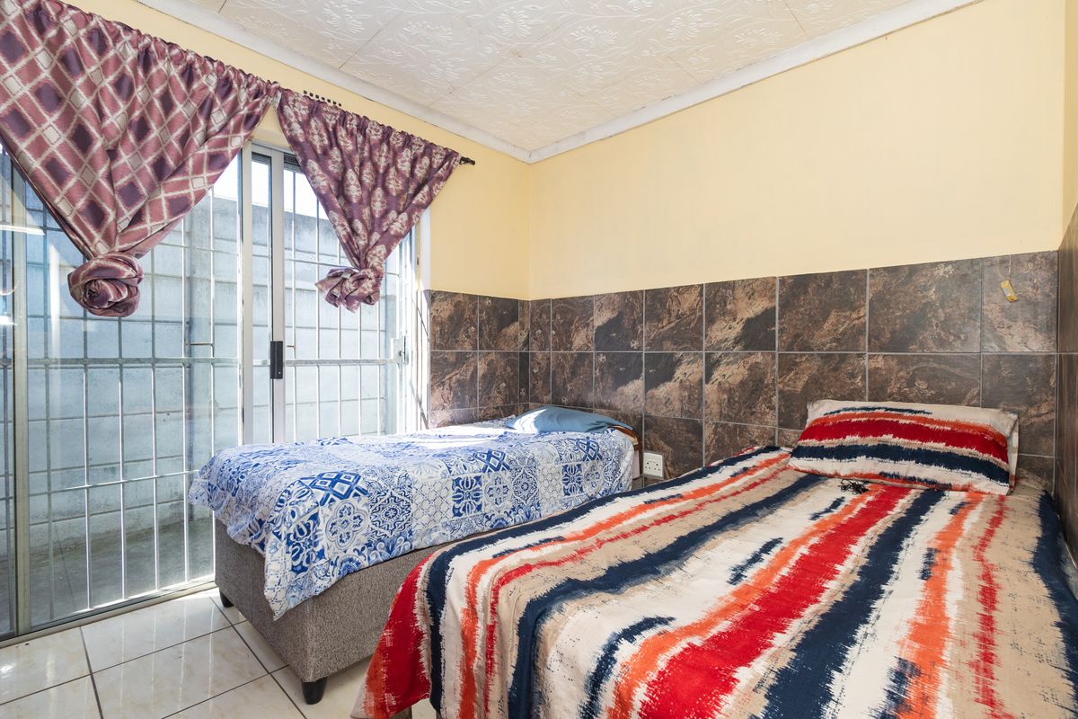 A bedroom featuring tiled flooring, tiled wall accents, and a sliding glass door with security gate access to the exterior.