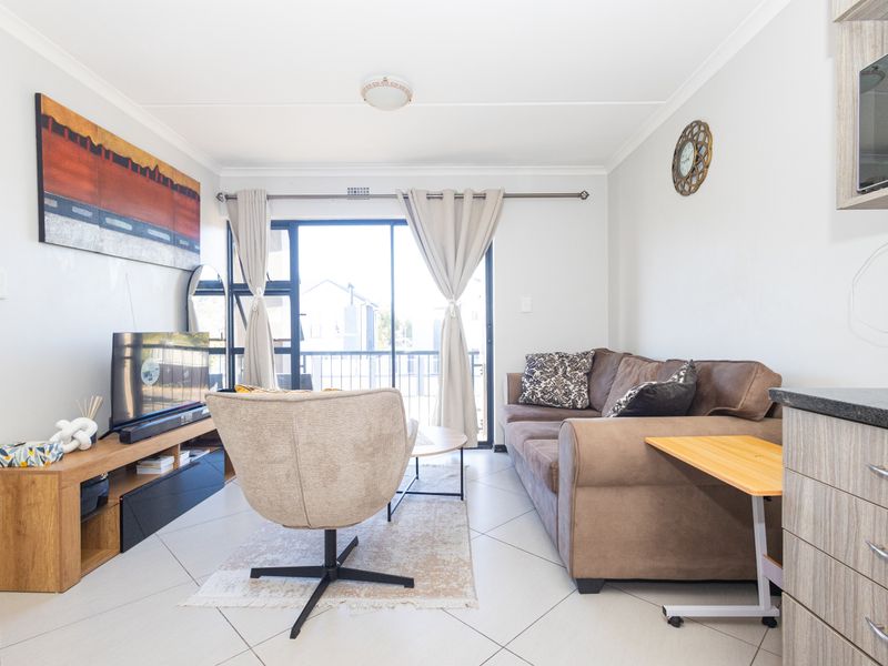 Open-plan living area featuring tiled flooring and a sliding glass door leading to a balcony, providing natural light and a functional layout.