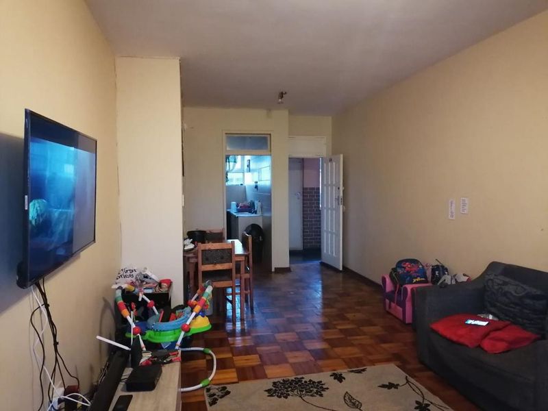 Open-plan living area featuring traditional parquet flooring and direct access to the kitchen and hallway.