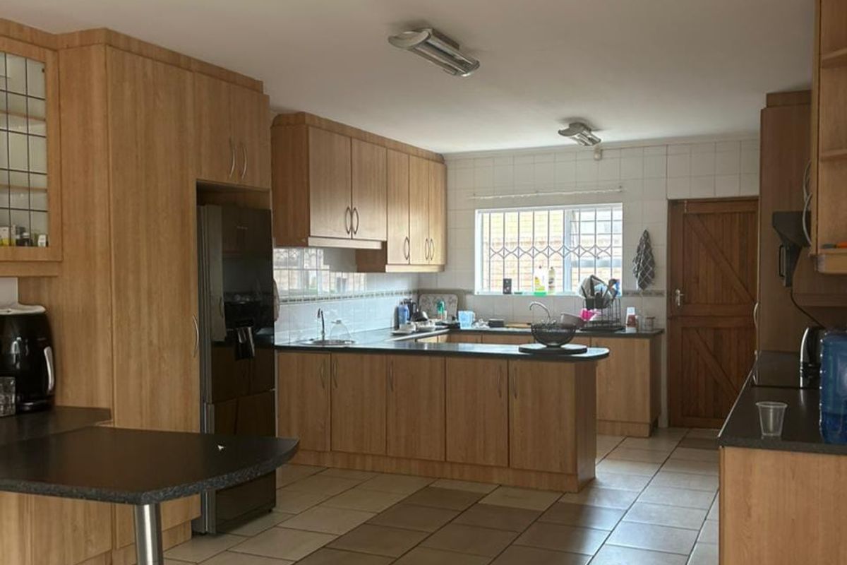 Spacious kitchen featuring light wood-finish cabinetry, dark laminate countertops, tiled flooring, and a functional layout with ample storage and workspace.