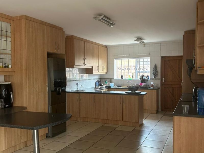 Spacious kitchen featuring light wood-finish cabinetry, dark laminate countertops, tiled flooring, and a functional layout with ample storage and workspace.