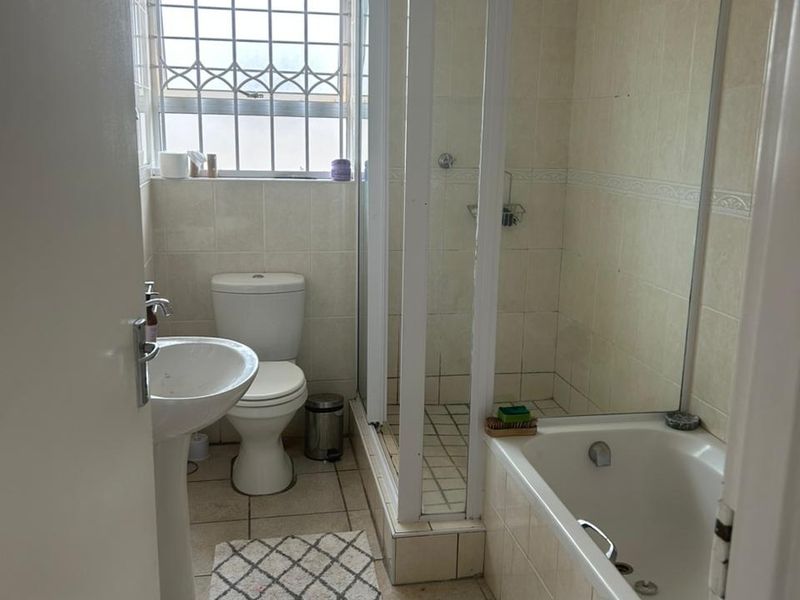 A functional bathroom featuring a pedestal basin, toilet, separate shower enclosure, and a bathtub with tiled finishes throughout.