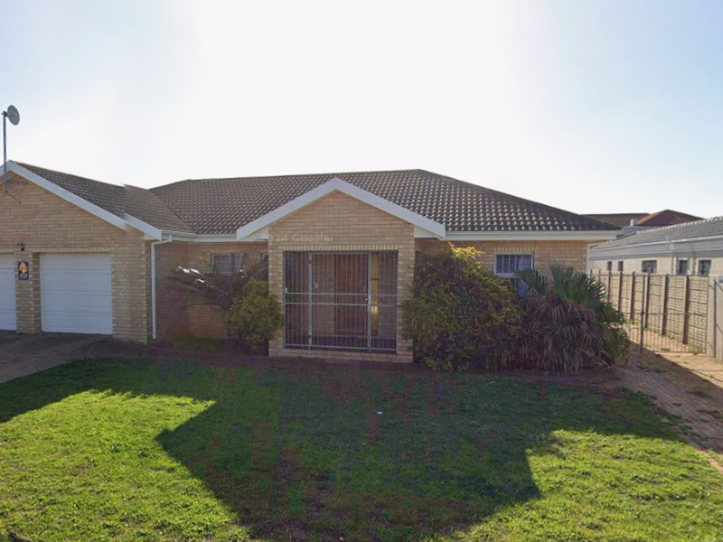 Front view of a single-story brick house featuring a double garage, tiled roof, and a paved driveway with a front garden.