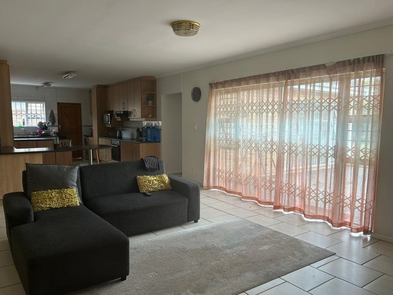 Open-plan living and kitchen area featuring tiled flooring, built-in cabinetry, and a large sliding door providing access to the outdoor space.