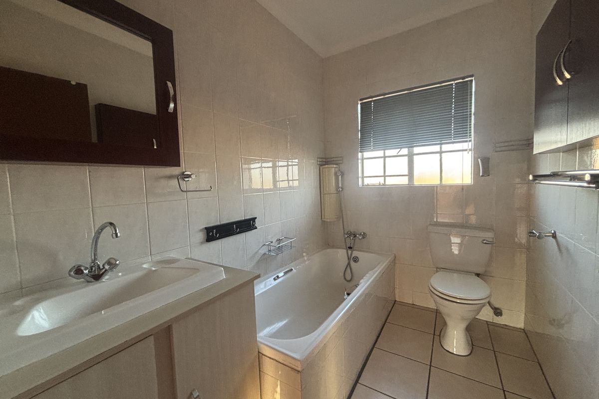 A functional bathroom featuring a bathtub, toilet, vanity basin, and tiled finishes, offering a clean and practical layout.