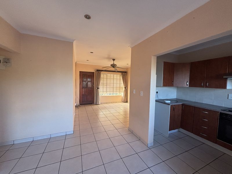 Open-plan living and kitchen area featuring tiled flooring, recessed lighting, and functional built-in cabinetry with integrated oven and extractor fan.