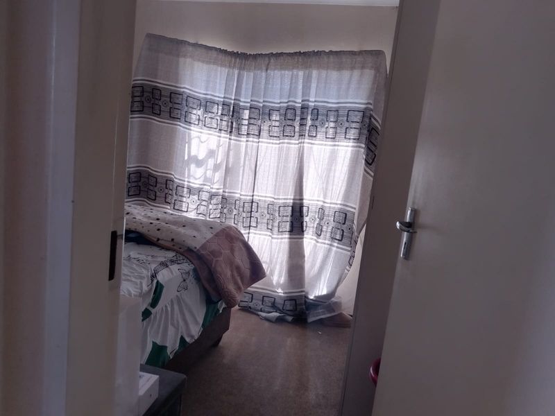 A view into a bedroom featuring a window with installed curtain rails, captured from the doorway.