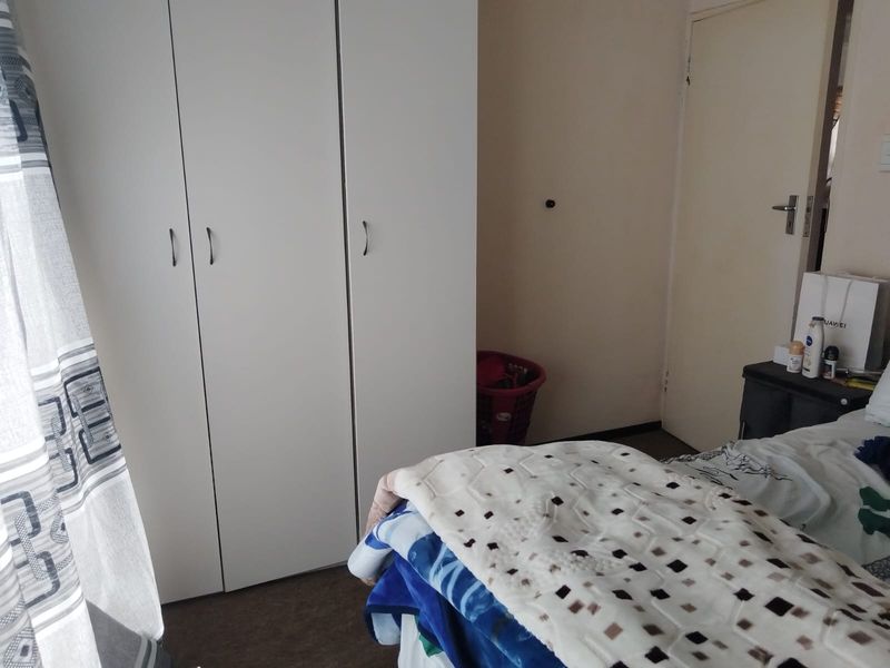 A bedroom featuring a white built-in wardrobe and a standard internal door, providing functional storage space.