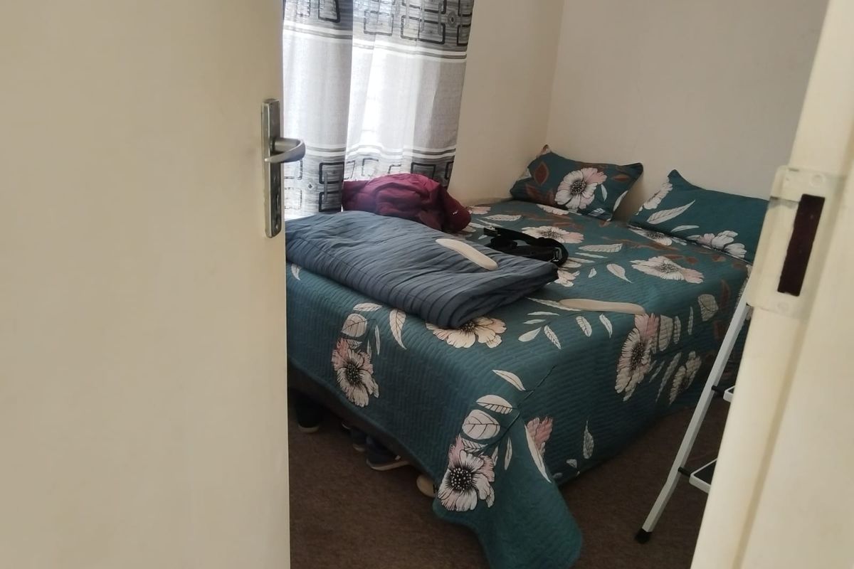 A compact bedroom featuring carpeted flooring and a window, providing a functional space for rest.