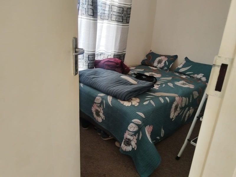 A compact bedroom featuring carpeted flooring and a window, providing a functional space for rest.