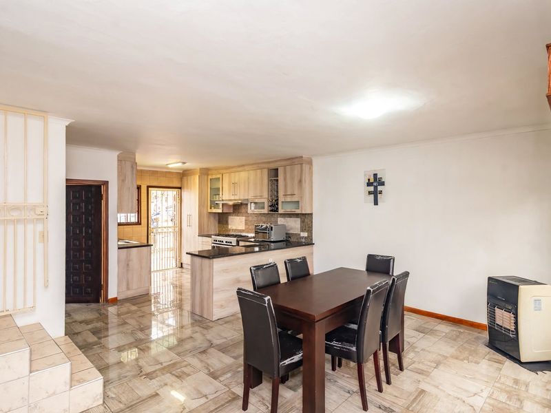 Open-plan living and dining area featuring a functional kitchen with granite countertops, gas stove, and tiled flooring throughout.