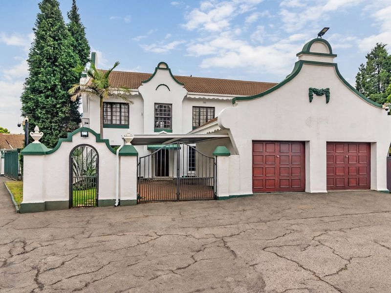 Front elevation of a townhouse featuring a double garage, gated entrance, and traditional architectural detailing with a tiled roof.