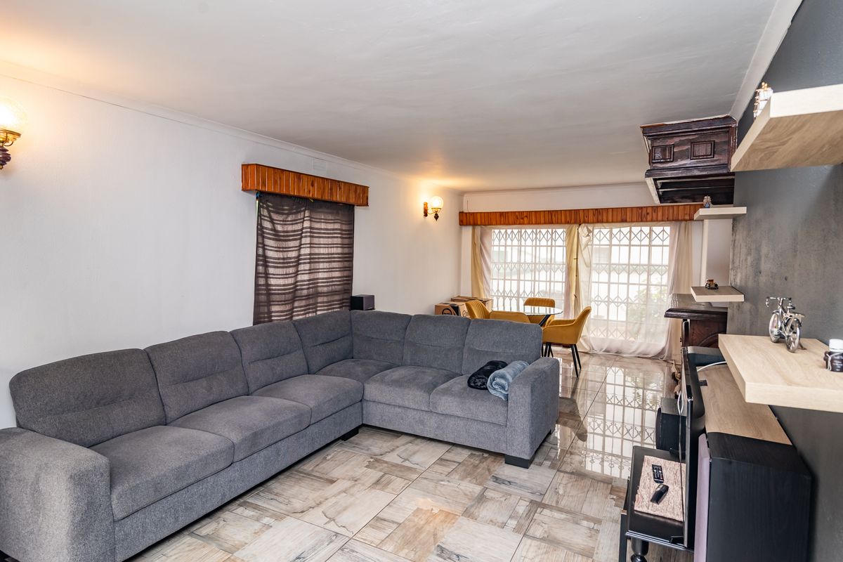 Spacious living room featuring tiled flooring, built-in shelving, and security gates on the windows, providing a functional and secure living space.