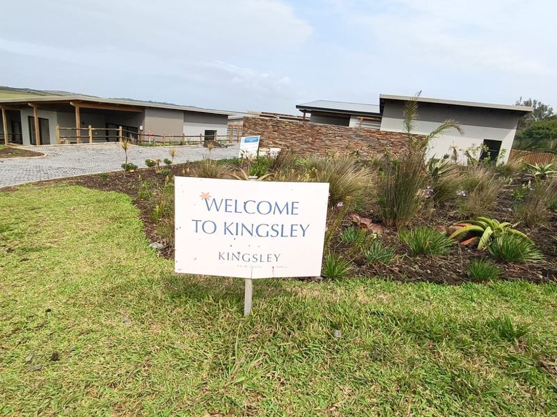 Front view of the Kingsley cluster development featuring a paved driveway, stone feature wall, and landscaped garden area.