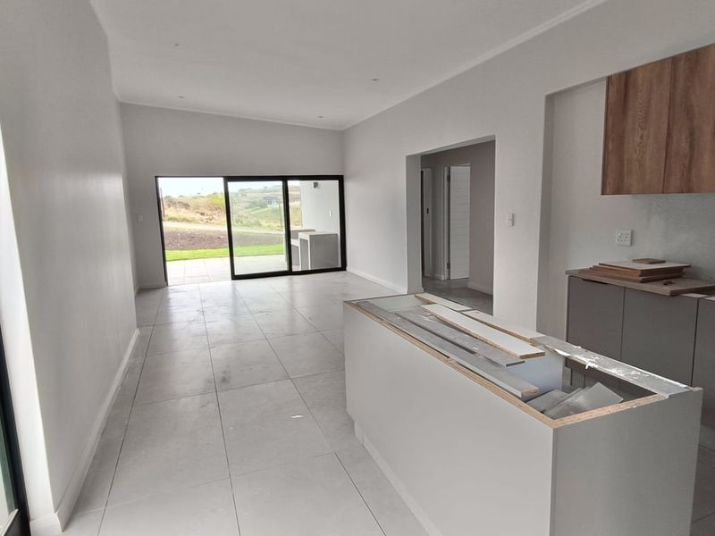 Open plan living and kitchen area featuring modern tiled floors, large sliding doors to the patio, and an unfinished kitchen island.