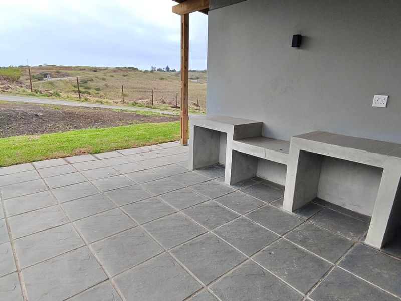 Covered patio area featuring a built-in concrete counter, tiled flooring, and direct access to the garden with scenic landscape views.