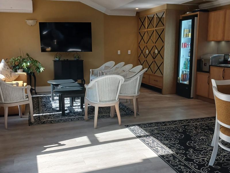 Spacious open-plan living area featuring light-toned laminate flooring, built-in cabinetry, and integrated air conditioning, suitable for communal retirement village activities.