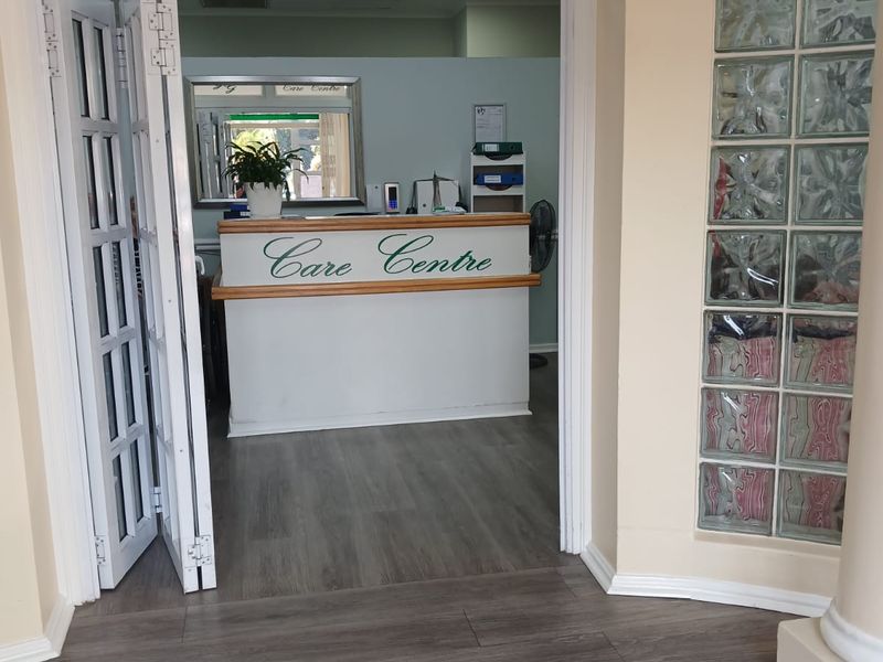 Entrance area leading into a care centre reception office, featuring glass block wall detailing, bi-fold doors, and modern laminate flooring.