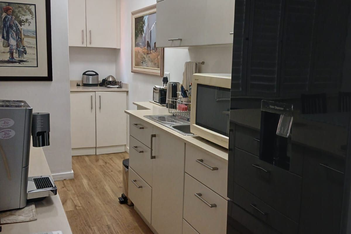 A functional kitchen featuring light-toned cabinetry, laminate flooring, and integrated appliances, offering a clean and practical workspace.