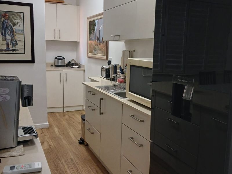 A functional kitchen featuring light-toned cabinetry, laminate flooring, and integrated appliances, offering a clean and practical workspace.