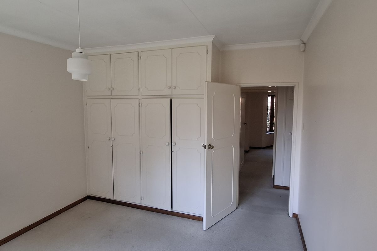 A vacant bedroom featuring built-in floor-to-ceiling cupboards, neutral wall finishes, and carpeted flooring, offering a blank canvas for personalization.