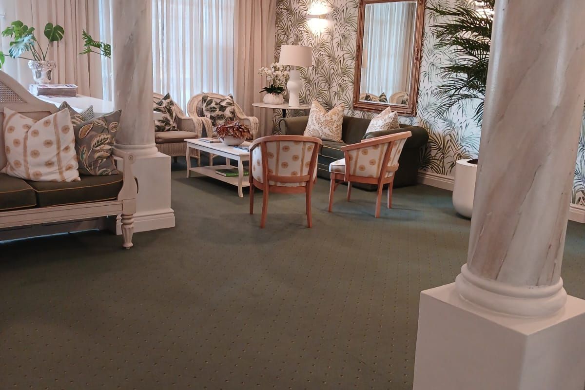 A spacious living area featuring decorative columns, recessed ceiling lighting, and elegant wall sconces, creating a sophisticated and well-lit atmosphere.