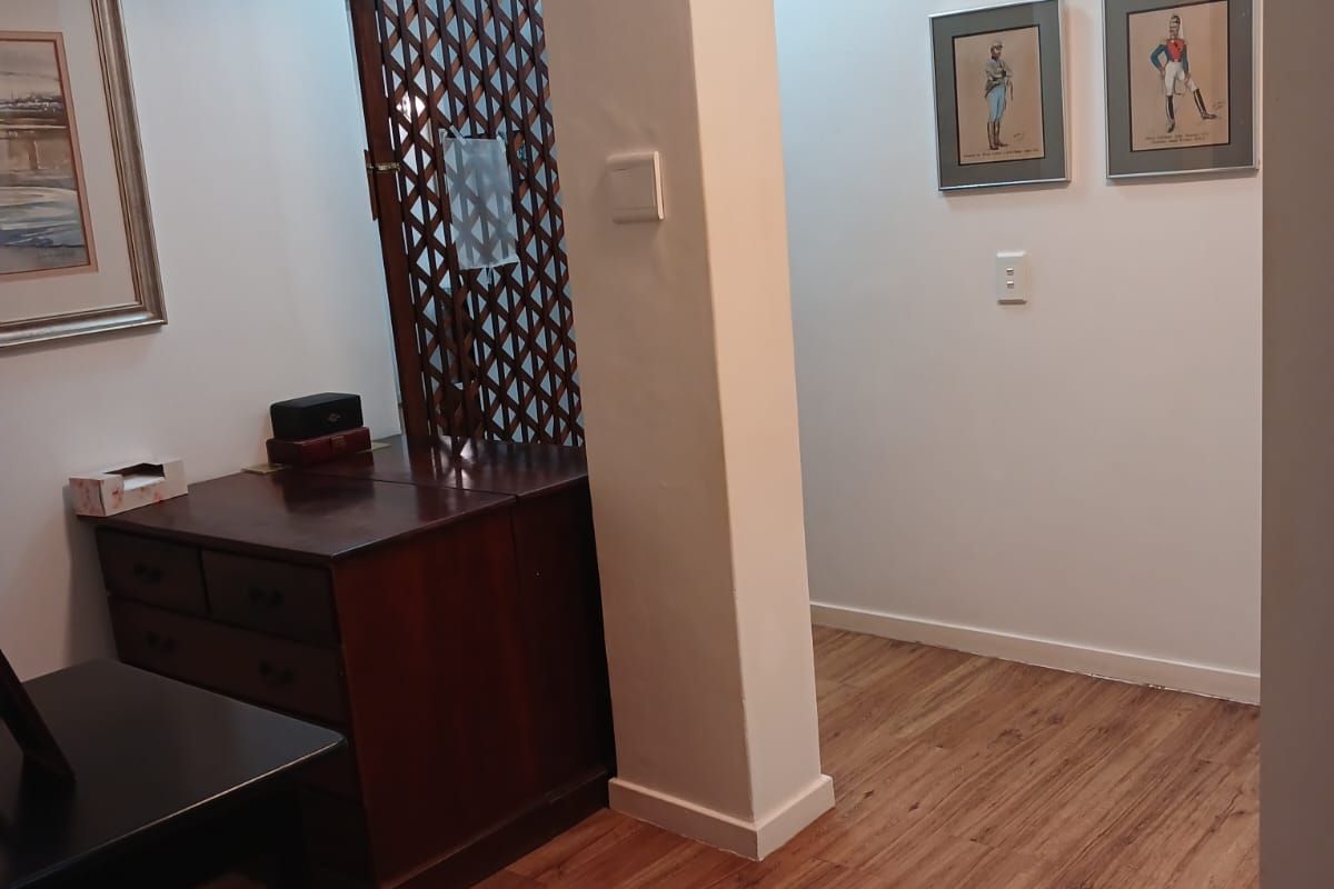 A bright hallway featuring laminate wood flooring, a structural pillar, and a skylight providing natural overhead illumination.
