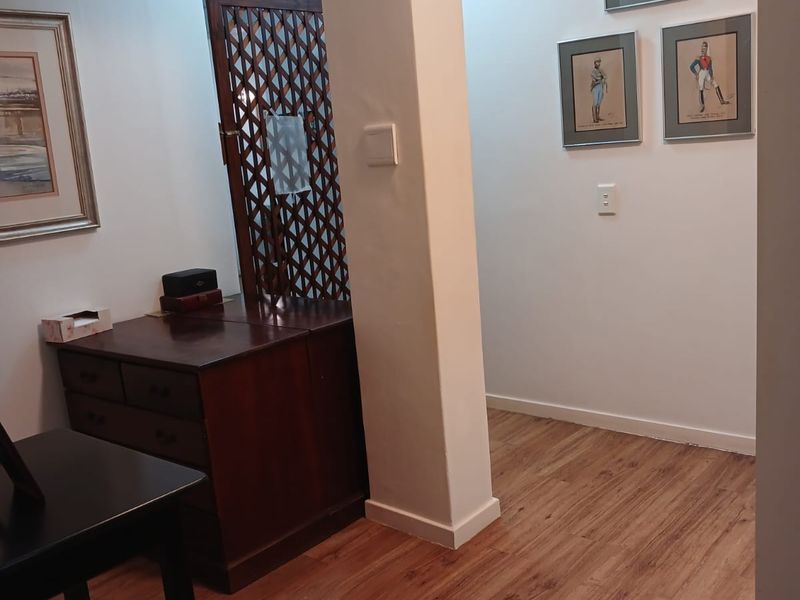 A bright hallway featuring laminate wood flooring, a structural pillar, and a skylight providing natural overhead illumination.