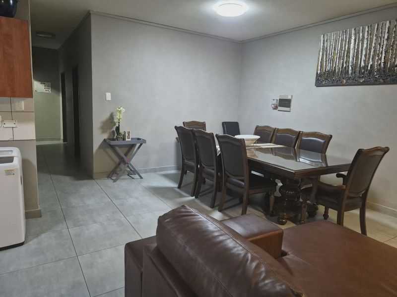 Open plan living and dining area featuring neutral wall tones and large format floor tiles, providing a functional and versatile space for daily living.