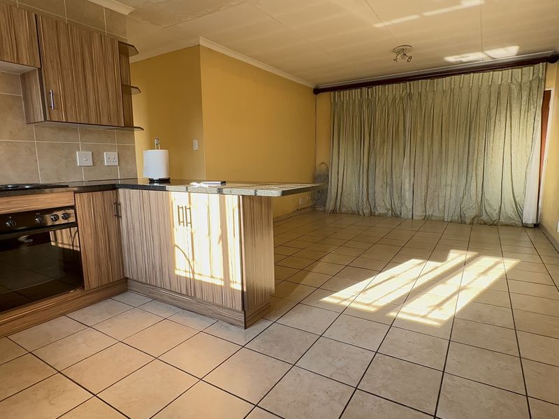 Open-plan kitchen and living area featuring tiled flooring, built-in cabinetry with granite countertops, and an integrated oven and hob.